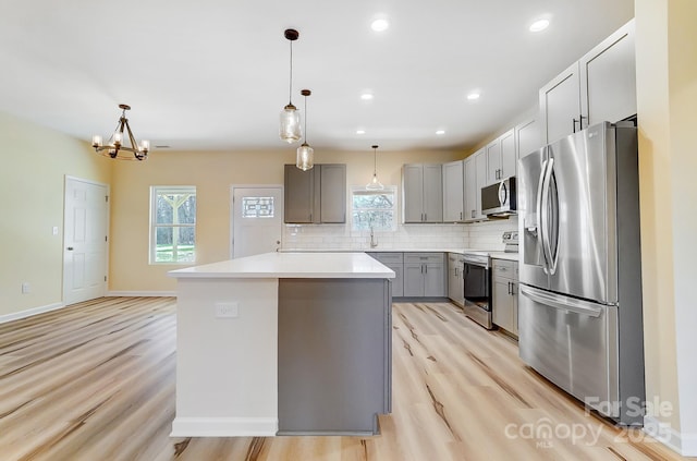 kitchen with decorative backsplash, gray cabinetry, stainless steel appliances, and light wood-type flooring