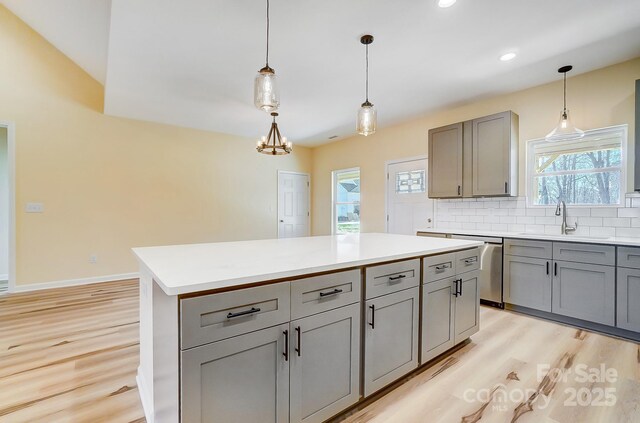 kitchen featuring tasteful backsplash, gray cabinetry, light countertops, light wood-style floors, and a sink