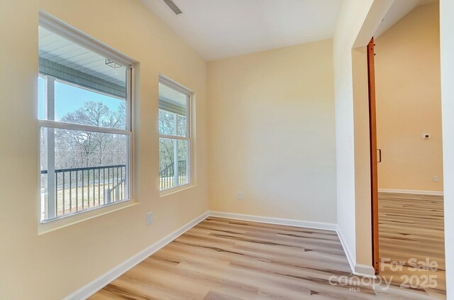 unfurnished room featuring light wood-style floors, visible vents, and baseboards