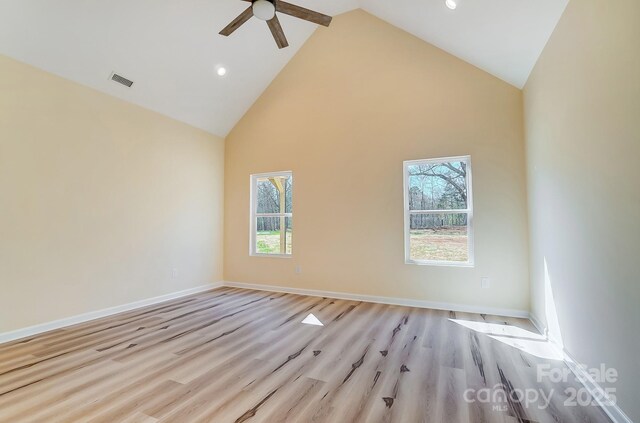 empty room featuring light wood finished floors, visible vents, ceiling fan, baseboards, and high vaulted ceiling