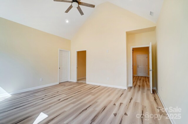 spare room with light wood-type flooring, baseboards, and high vaulted ceiling