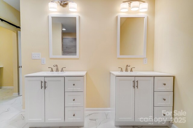 full bath with a sink, two vanities, and marble finish floor