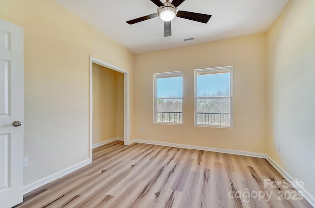 empty room with visible vents, a ceiling fan, baseboards, and wood finished floors