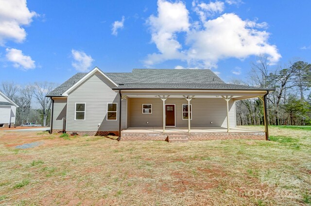 rear view of property featuring crawl space, a yard, and a shingled roof