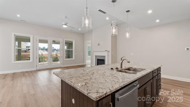 kitchen with visible vents, open floor plan, dark brown cabinetry, a sink, and dishwasher