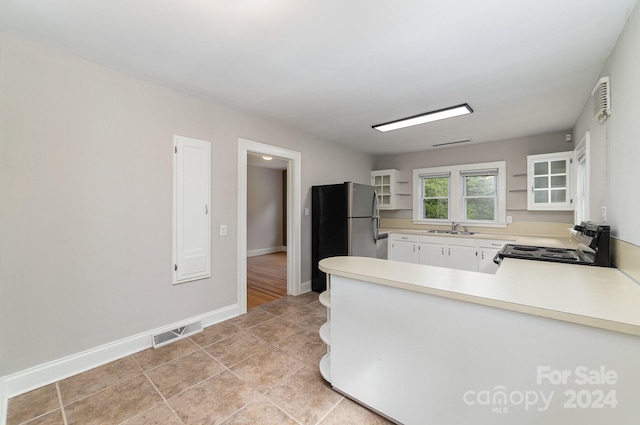 kitchen with black range with electric stovetop, white cabinetry, stainless steel refrigerator, sink, and kitchen peninsula