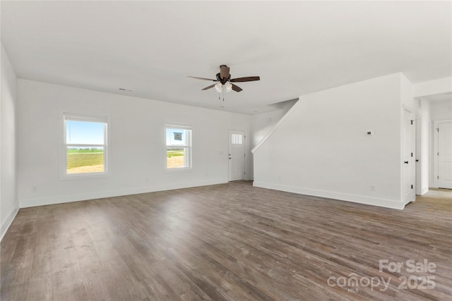 unfurnished living room with ceiling fan, wood finished floors, and baseboards