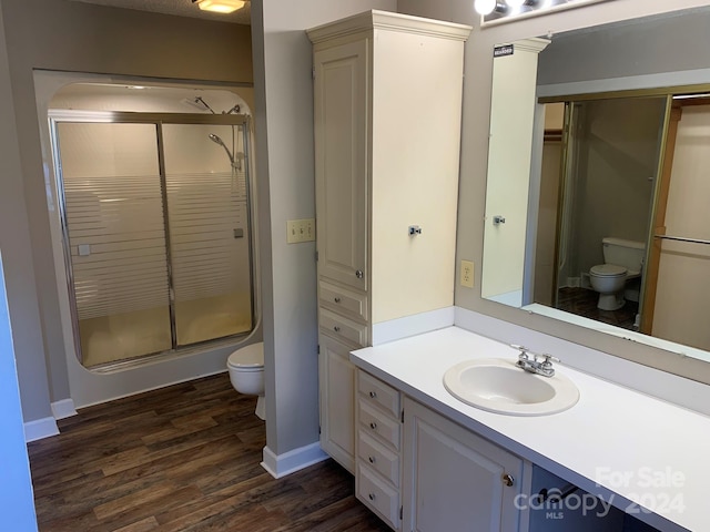 bathroom with walk in shower, wood-type flooring, vanity, and toilet