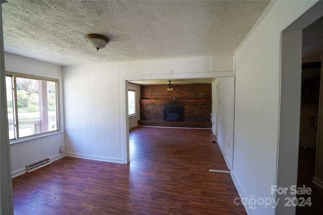 unfurnished living room with dark hardwood / wood-style flooring, a textured ceiling, and a wood stove