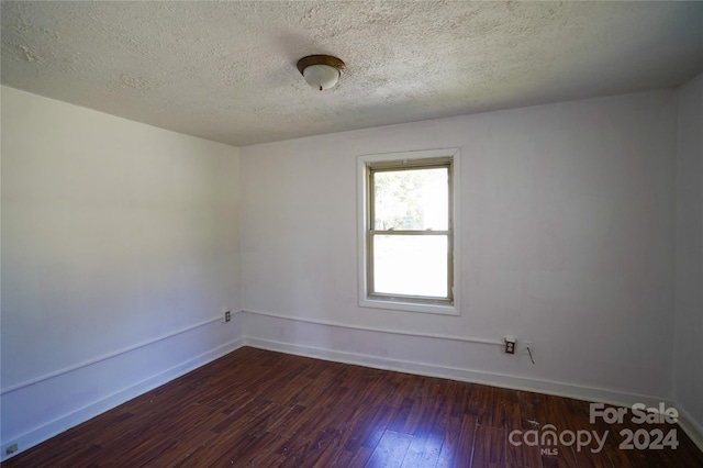 unfurnished room featuring dark hardwood / wood-style flooring and a textured ceiling