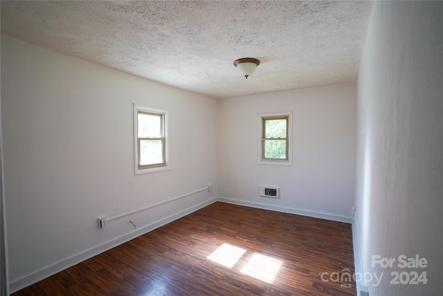 unfurnished room featuring a textured ceiling and dark hardwood / wood-style flooring