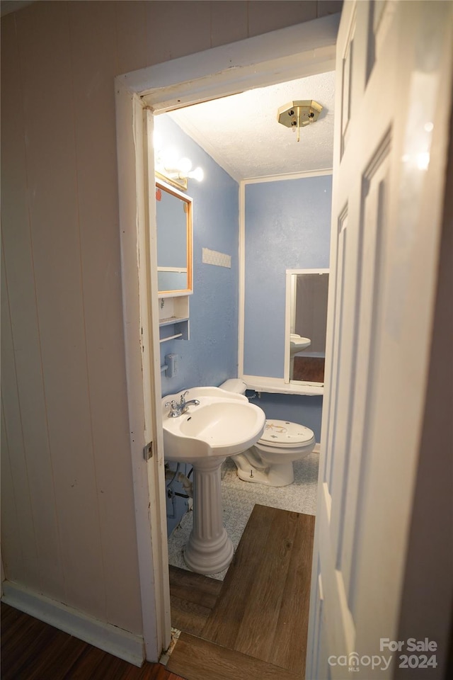 bathroom with hardwood / wood-style flooring, wooden walls, and toilet