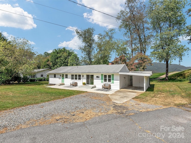 ranch-style home featuring a carport and a front yard