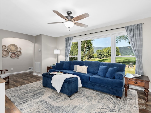 living room with dark wood-type flooring and ceiling fan