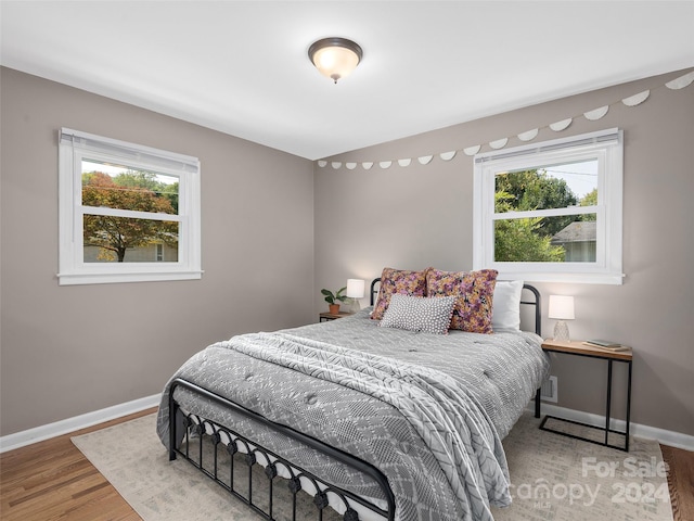 bedroom with hardwood / wood-style flooring and multiple windows