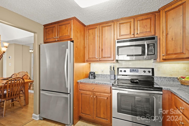 kitchen with light wood-type flooring, tasteful backsplash, a textured ceiling, stainless steel appliances, and stone countertops