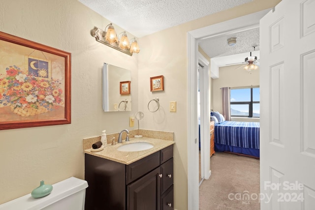 bathroom featuring ceiling fan, toilet, a textured ceiling, and vanity