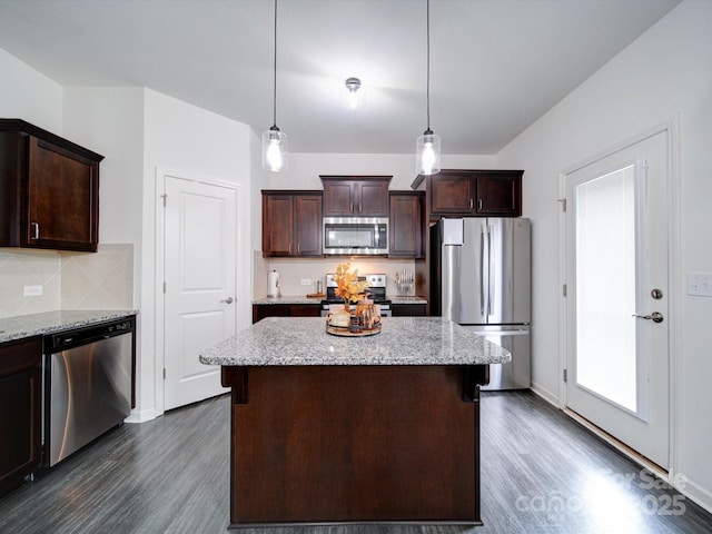 kitchen with dark brown cabinets, stainless steel appliances, light stone counters, and hanging light fixtures