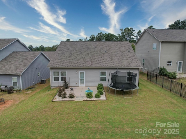 rear view of house with a trampoline, a yard, a patio, and central AC