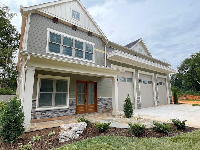 craftsman-style home with covered porch, a garage, and french doors