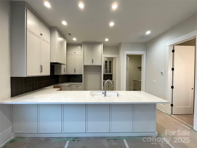 kitchen featuring white cabinetry, sink, backsplash, and kitchen peninsula