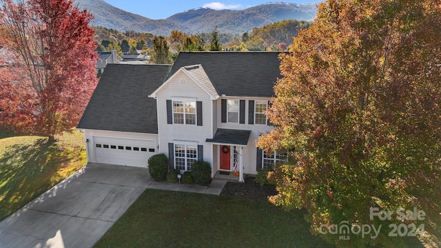 view of front of home featuring a mountain view, a front lawn, and a garage