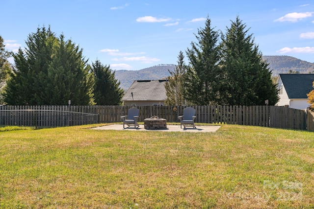 view of yard featuring an outdoor fire pit, a mountain view, and a patio