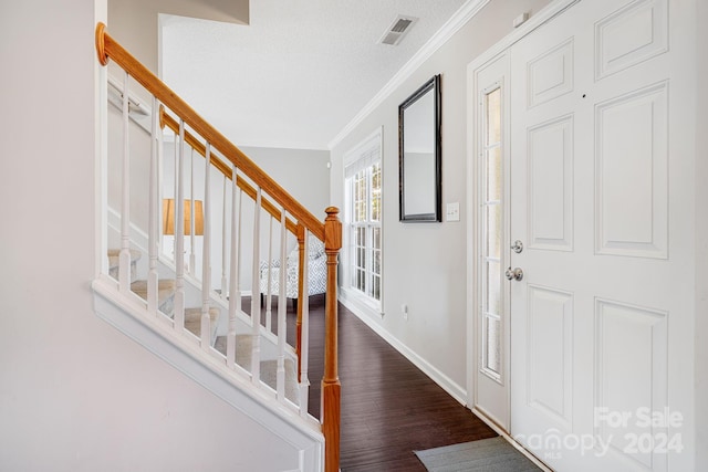 entryway with ornamental molding, a textured ceiling, and dark hardwood / wood-style flooring