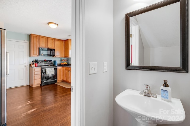 bathroom with lofted ceiling, a textured ceiling, sink, and wood-type flooring