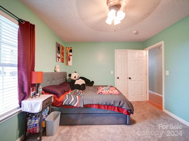 carpeted bedroom featuring ceiling fan and a textured ceiling