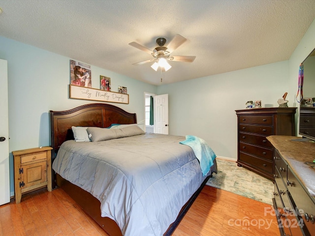 bedroom with light hardwood / wood-style flooring, ceiling fan, and a textured ceiling