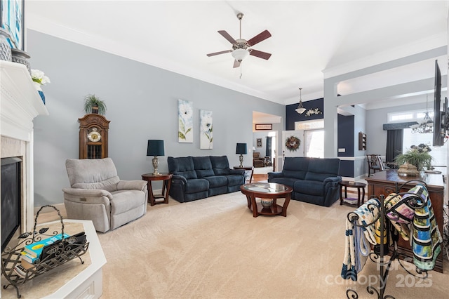 living room with light colored carpet, a tiled fireplace, ceiling fan with notable chandelier, and ornamental molding