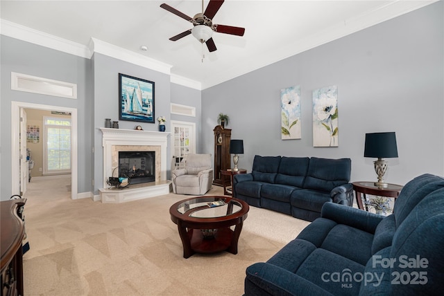 living room featuring ceiling fan, light colored carpet, a tiled fireplace, and ornamental molding