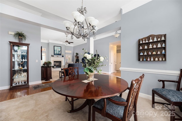 carpeted dining area featuring ornamental molding and ceiling fan with notable chandelier