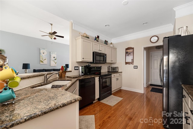 kitchen with black appliances, sink, ornamental molding, kitchen peninsula, and light wood-type flooring