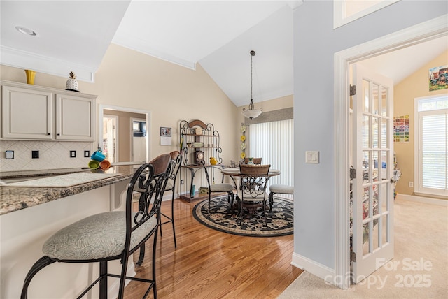 kitchen with stone countertops, plenty of natural light, backsplash, and vaulted ceiling