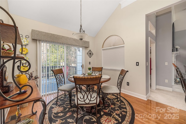 dining space with high vaulted ceiling and light hardwood / wood-style floors