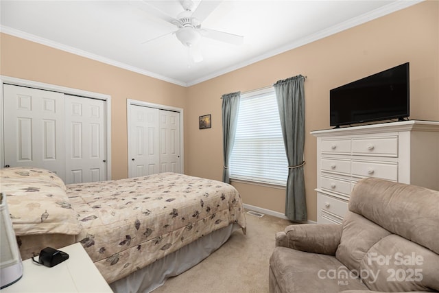 carpeted bedroom with ceiling fan, crown molding, and two closets