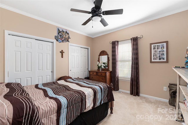 carpeted bedroom featuring ceiling fan, multiple closets, and ornamental molding