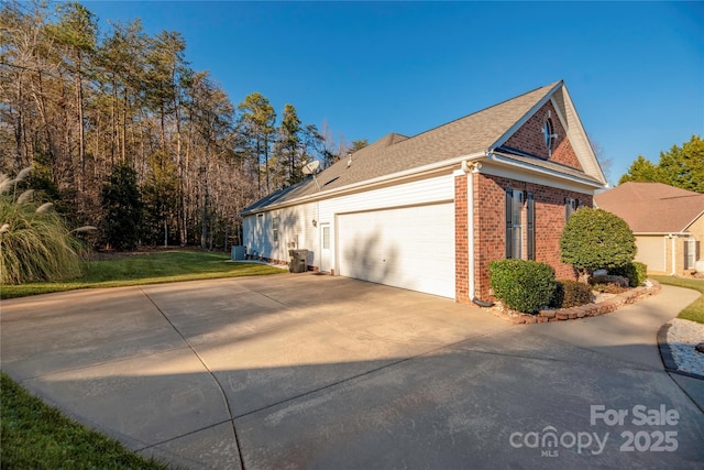 view of side of home with a garage, cooling unit, and a lawn