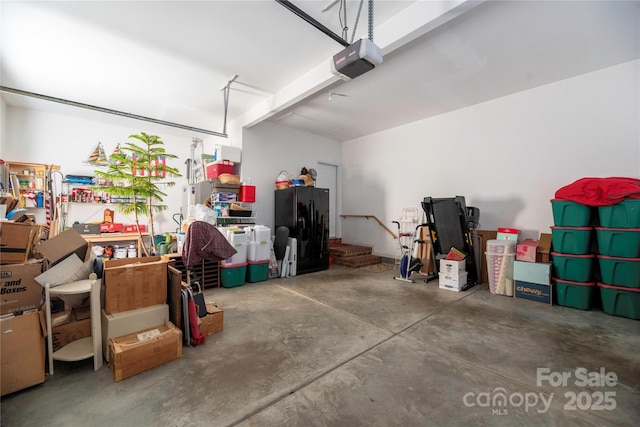 garage featuring black refrigerator with ice dispenser and a garage door opener