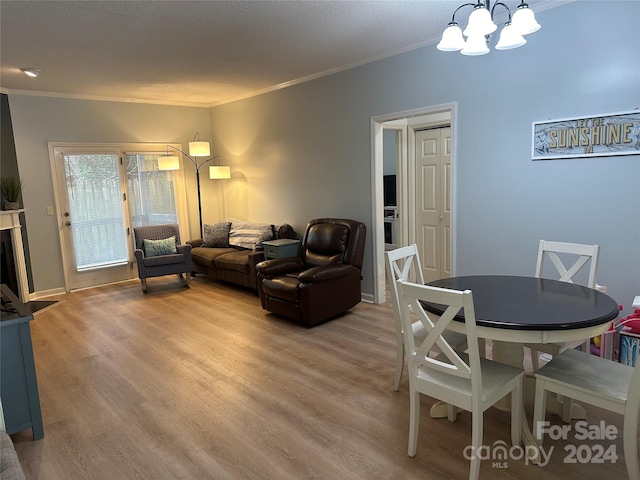 dining space with light hardwood / wood-style flooring, an inviting chandelier, a textured ceiling, and ornamental molding