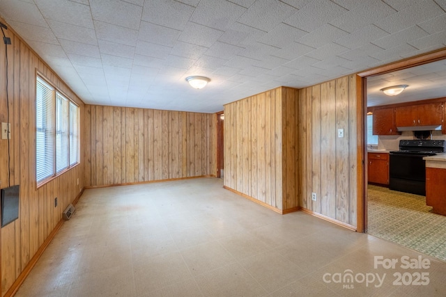 interior space with light floors, wooden walls, and baseboards