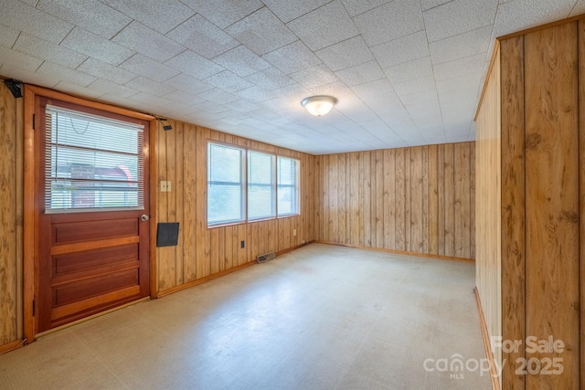 unfurnished room featuring baseboards, wooden walls, and light floors