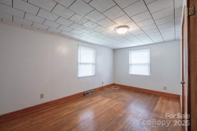 unfurnished room featuring visible vents, baseboards, and wood finished floors