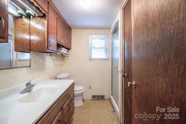 bathroom featuring vanity, toilet, and a shower with door