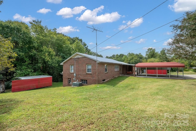 rear view of property with a yard, central AC, a carport, and a storage unit