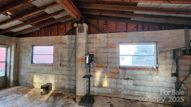 interior space featuring concrete block wall, concrete floors, and vaulted ceiling