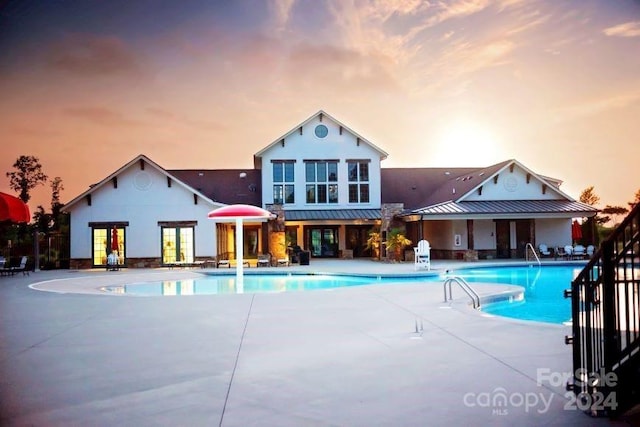 pool at dusk featuring a patio