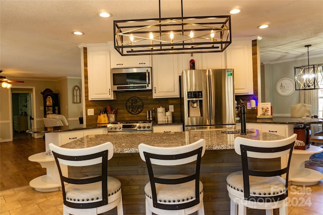 kitchen featuring a kitchen breakfast bar, ceiling fan with notable chandelier, and appliances with stainless steel finishes